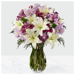 Bouquet of white lilies and pink mixed flowers in a glass vase