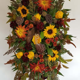Tall standing floral spray with sunflowers, roses, and autumn foliage