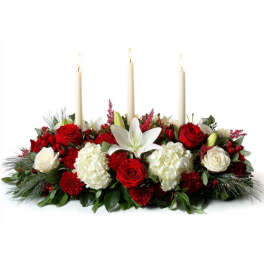 Red and white floral centerpiece with three lit taper candles