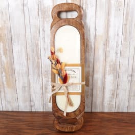 Rustic wooden tray candle with white wax and a small bundle of dried flowers tied with a ribbon.