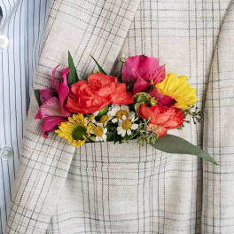 Small bouquet of pink, red, and yellow flowers pinned to a plaid jacket