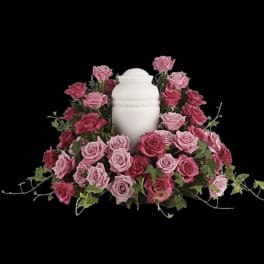 Pink roses arranged around a white urn on a black background