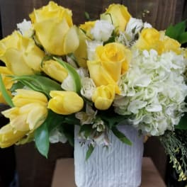 Yellow roses and white hydrangeas arranged in a white vase