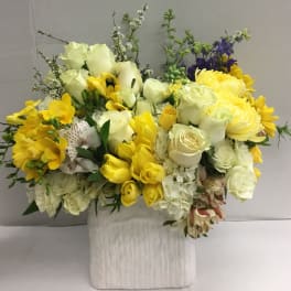 Yellow and white mixed flower arrangement in a white vase