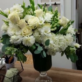 White roses and mixed white flowers in a dark glass vase