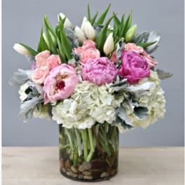 Pink and white flowers arranged in a glass vase with pebbles