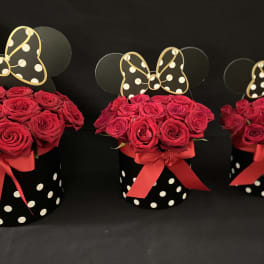 Three red rose arrangements in black polka-dot boxes with bow toppers