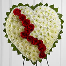 Heart-shaped white floral spray with red roses on an easel