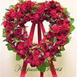 Heart-shaped wreath of red roses and carnations with a ribbon bow