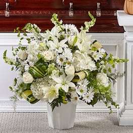 White floral arrangement in a white vase with lilies and daisies