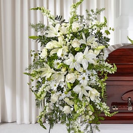 White funeral spray with lilies and roses on a stand