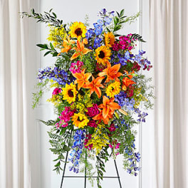 Tall standing spray with sunflowers, lilies, and blue flowers