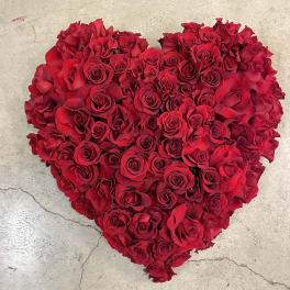 Heart-shaped arrangement of red roses on a stone surface