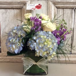 Bouquet of pastel hydrangeas, purple stock, and cream roses in a green vase
