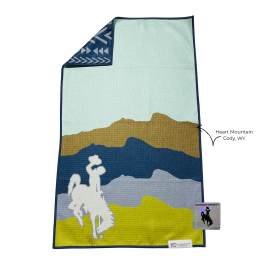 Folded blanket with a mountain scene and cowboy silhouette