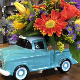 Colorful flower arrangement in a turquoise ceramic truck container