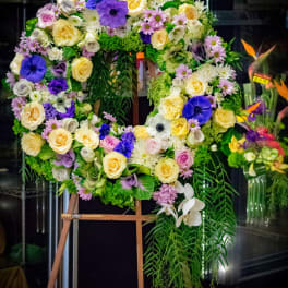 Large floral wreath on an easel with purple, yellow, white, and pink flowers