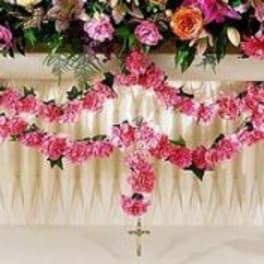 Pink floral cross arrangement on a white draped stand