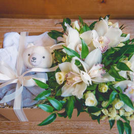 White orchid bouquet in a gift box with a teddy bear and ribbon
