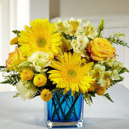 Yellow and white mixed bouquet in a blue glass vase