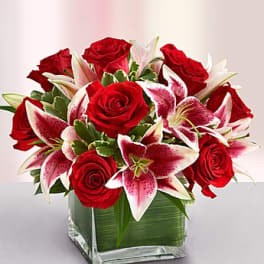 Red roses and pink lilies in a square glass vase