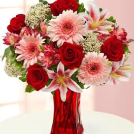 Bouquet of red roses, pink gerbera daisies, and lilies in a red vase