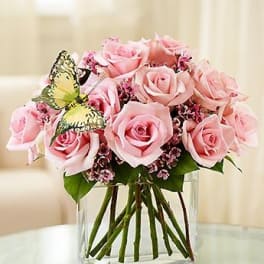Pink rose bouquet in a clear glass vase with a butterfly decoration