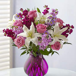 Pink roses and white lilies in a purple glass vase