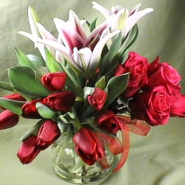 Bouquet of red roses and pink lilies in a clear glass vase