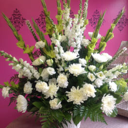 Tall white floral arrangement in a white vase with green accents