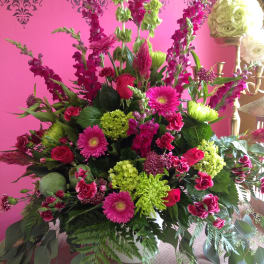 Large pink and green floral arrangement in a white vase