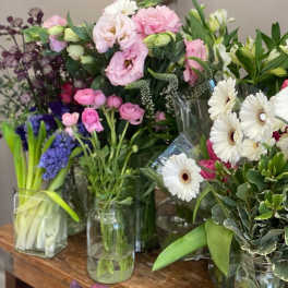 Assorted bouquets of pink, white, and purple flowers in glass vases