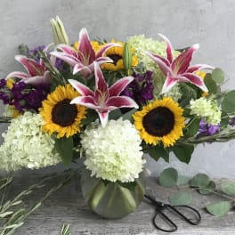Bouquet of pink lilies, sunflowers, and white hydrangeas in a vase