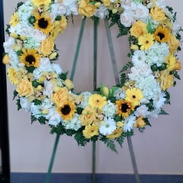 Circular floral wreath with yellow and white flowers on a stand
