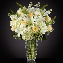 White and pale yellow floral arrangement in a clear glass vase