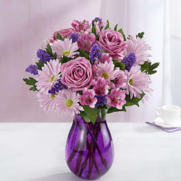 Pink and purple mixed bouquet in a purple glass vase