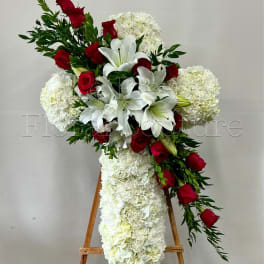 Cross-shaped floral arrangement with white lilies, red roses, and white hydrangeas