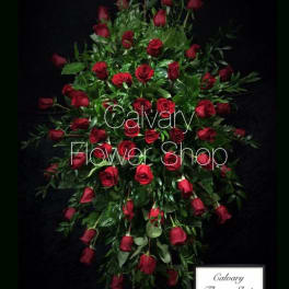 Standing spray of red roses with greenery on a black background