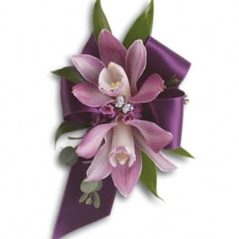Purple orchid corsage with ribbon and green leaves
