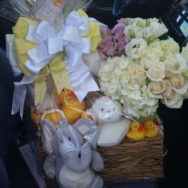 Basket of white and lavender flowers with plush toys and ribbon bows
