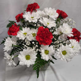 Bouquet of red carnations and white daisies in a clear glass vase
