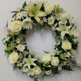 White floral wreath with roses, lilies, and daisies