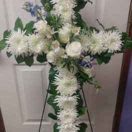 White floral cross on a stand with roses and chrysanthemums