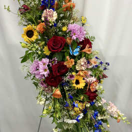 Tall mixed flower arrangement with roses, sunflowers, and blue blooms