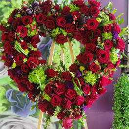Heart-shaped floral wreath of red roses with green accents on an easel