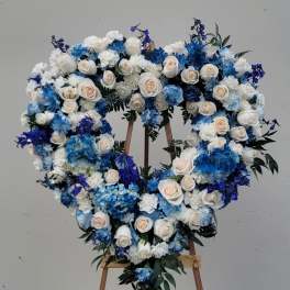 Heart-shaped floral wreath of white and blue roses on an easel