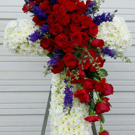 Standing floral cross with red roses, white chrysanthemums, and purple accents