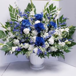 Blue and white floral arrangement in a white pedestal vase