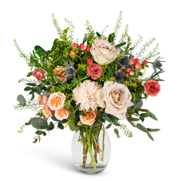 Bouquet of cream and peach roses with white blooms in a clear glass vase