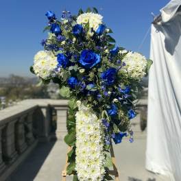 Blue and white floral cross on an easel outdoors